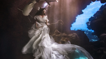 Модель-фридайвер позирует под водой среди акул